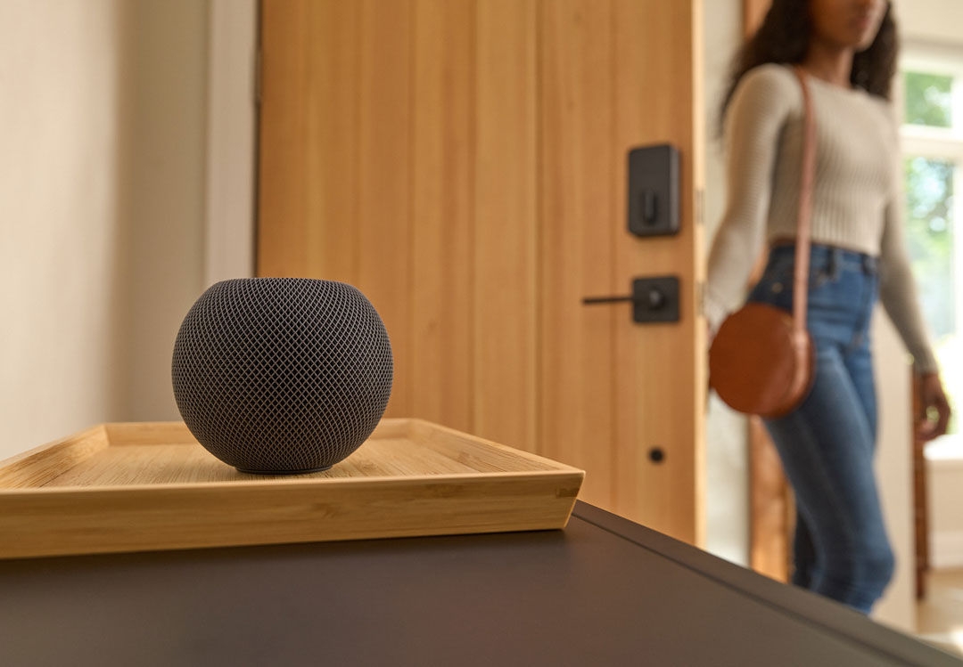 Woman enters home using Sense Pro Ultra Wideband smart lock for hands-free unlocking set up with Apple Home Pod