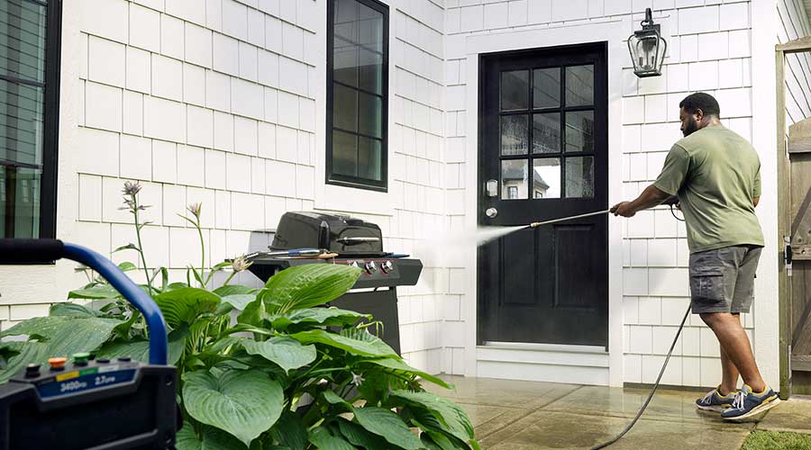 Man using a hose to wash his grill