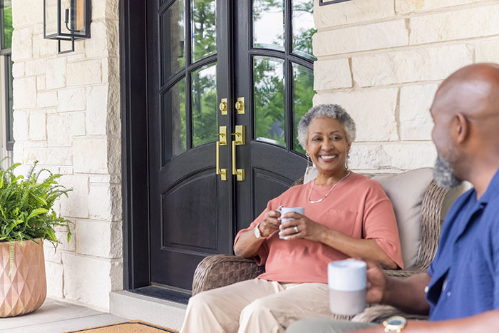 independent-living-couple-sitting-on-front-porch-with-coffee