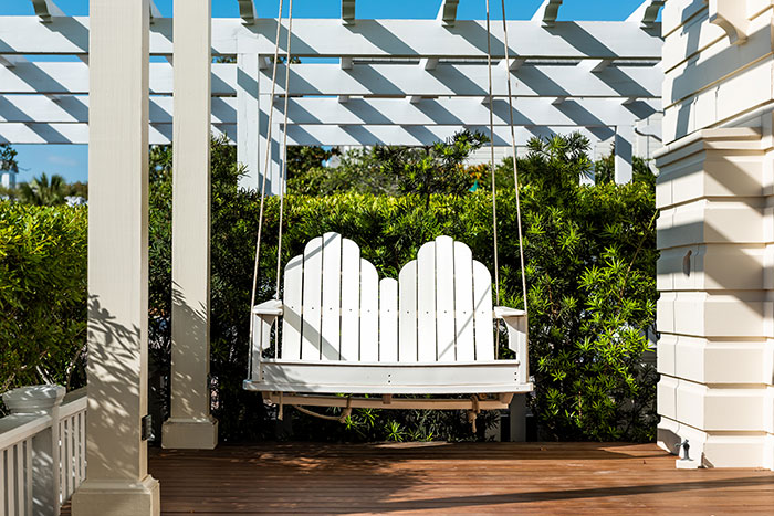 Patio lounge white wooden new hanging swing in outdoor spring green garden in backyard porch of home zen, hanging furniture, nobody in Florida tropical cottage vacation home